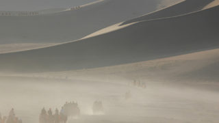 敦煌鳴沙山。朝日をあびて砂山の稜線がくっきりと浮かびあがる。足に鈴をつけた駱駝が１日の活動をはじめる