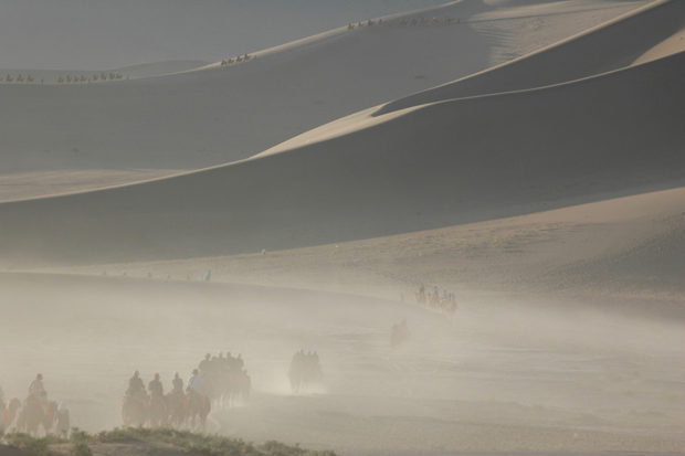 敦煌鳴沙山。朝日をあびて砂山の稜線がくっきりと浮かびあがる。足に鈴をつけた駱駝が１日の活動をはじめる